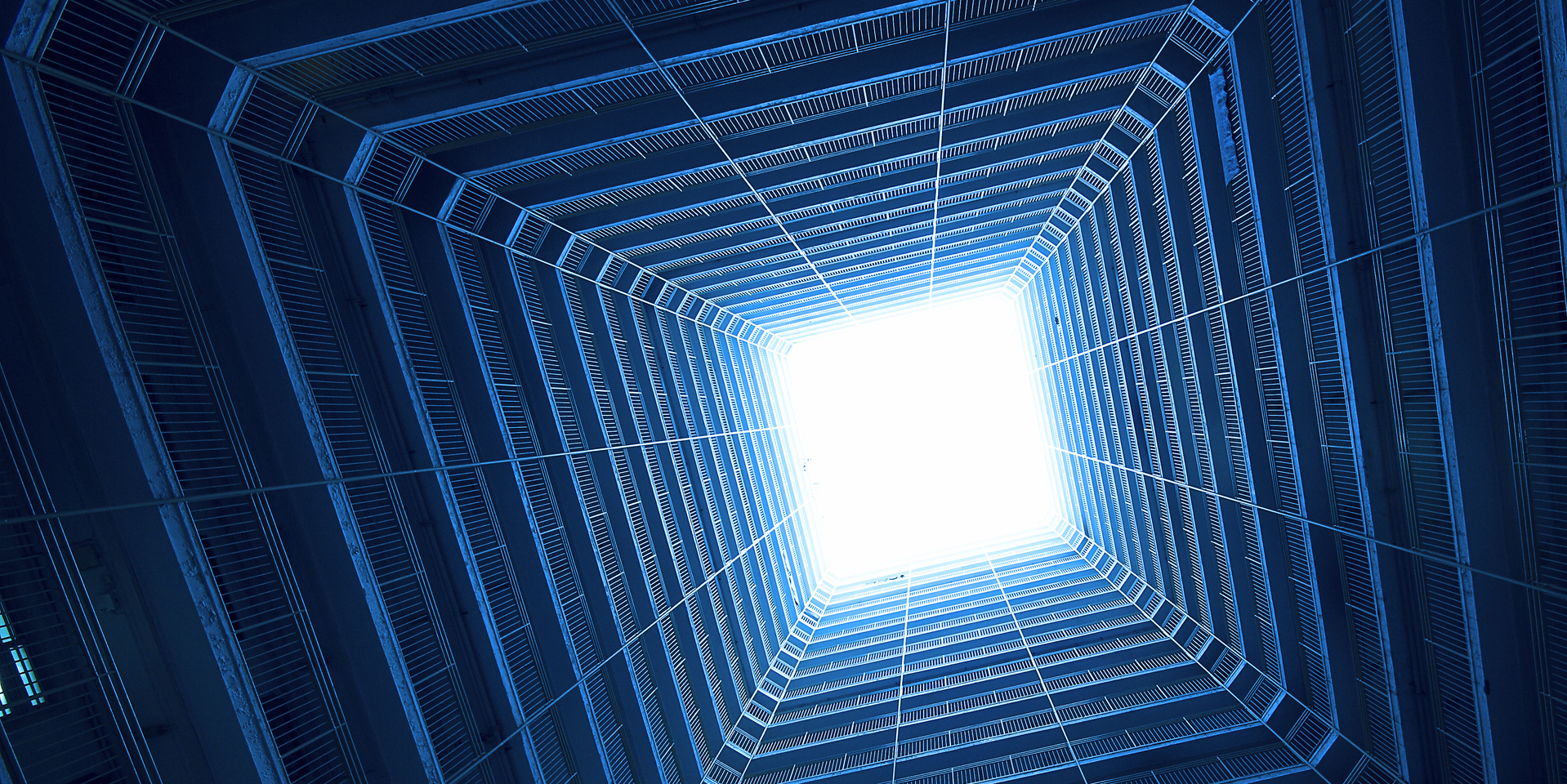 Square building in blue tone with sky in background.