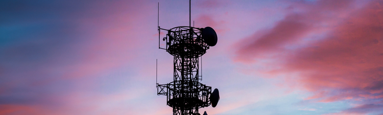 Medium angle of silhouetted communications tower at sunset.