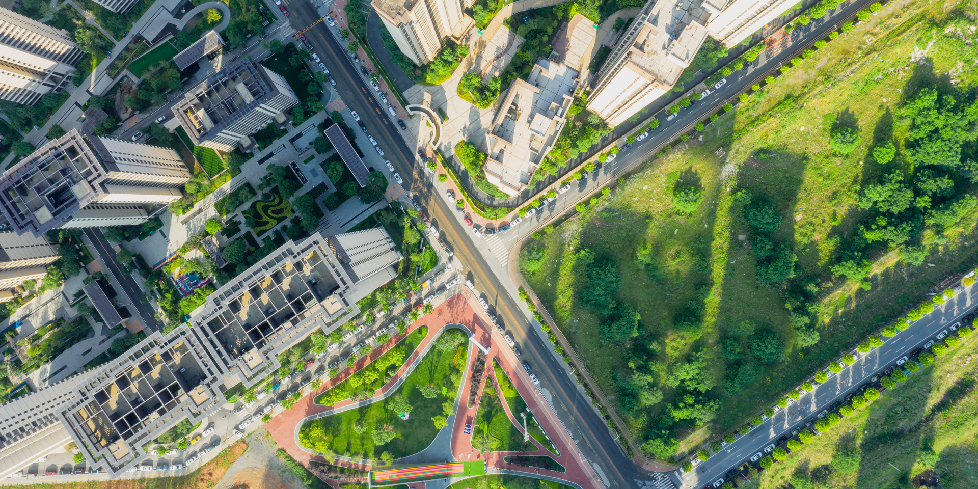 High angle down of green park space near residential buildings and office towers.
