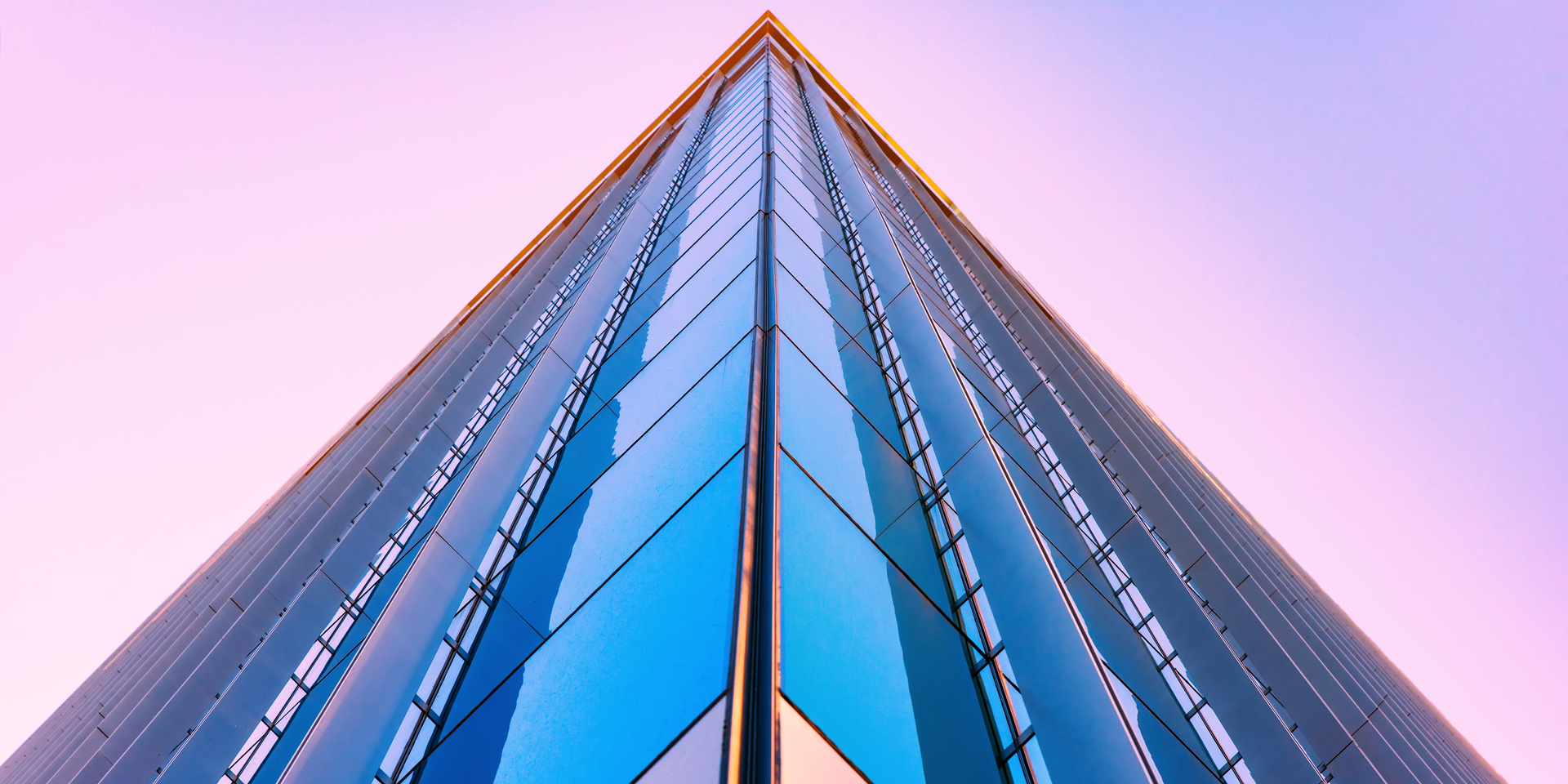 Up angle of glass skyscraper at sunset.