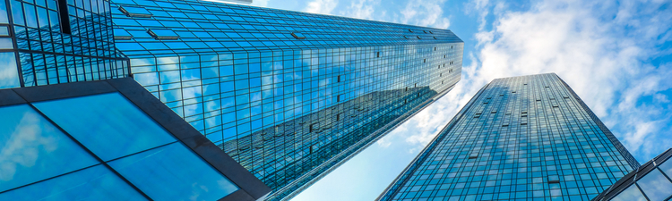 Bottom view of modern skyscrapers in business district against blue sky
