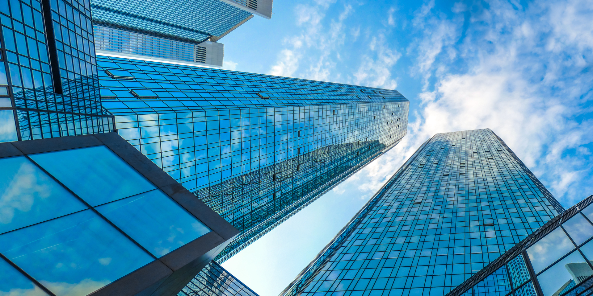 Bottom view of modern skyscrapers in business district against blue sky
