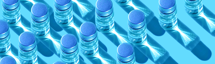 Overhead angle of metal-lidded glass vials containing clearly liquid.