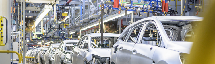 Wide angle of cars on factory assembly line.