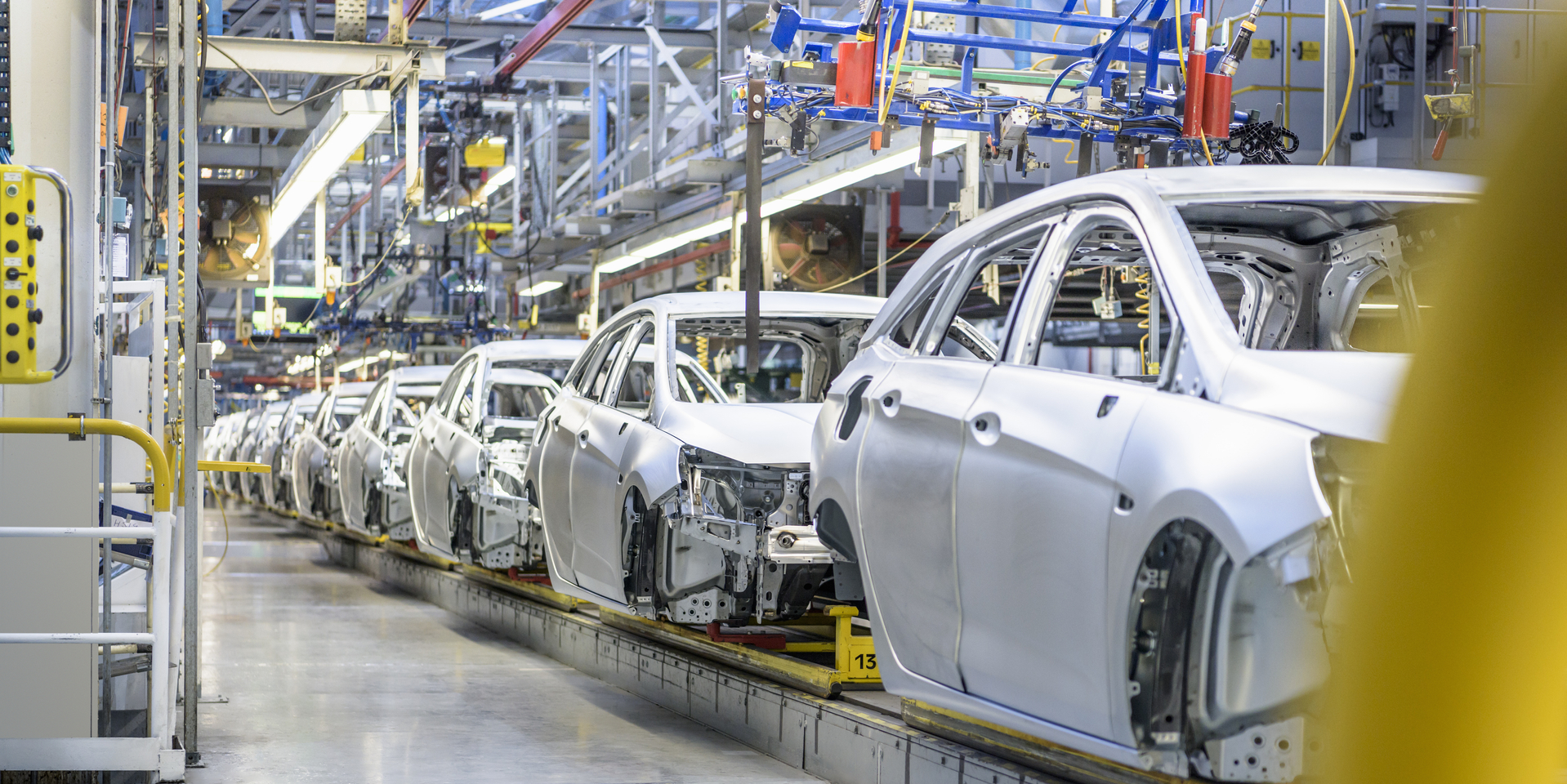 Wide angle of cars on factory assembly line.