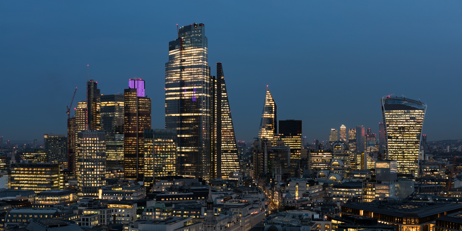 An elevated view of the City of London’s illuminated financial district skyline at night.