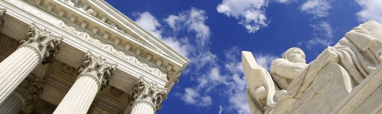 Up angle of the Authority of Law statue in front of the West Facade of the United States Supreme Court Building.