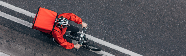 Bike delivery rider on bike carrying red cooler on his back.