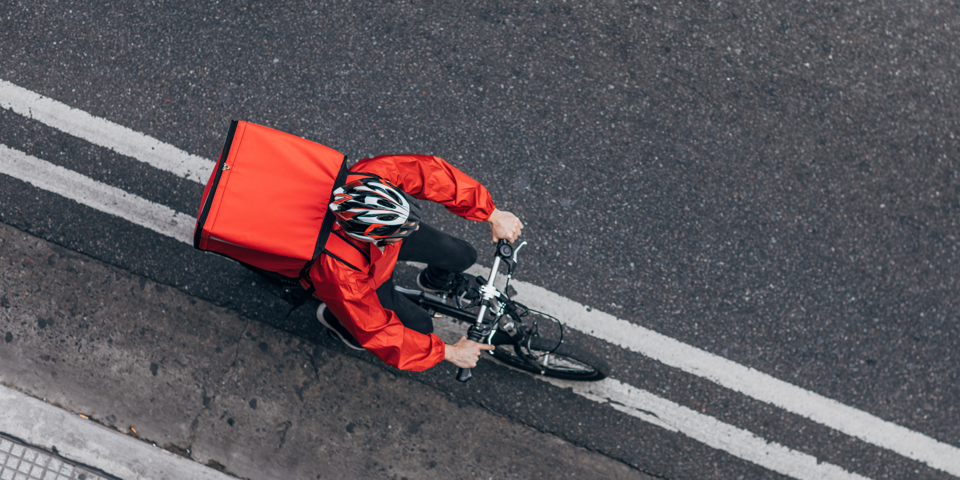 Bike delivery rider on bike carrying red cooler on his back.