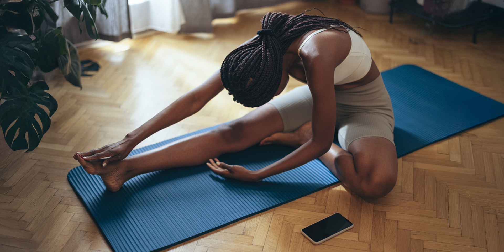 High angle down of woman in sportswear stretching on blue exercise mat at home.