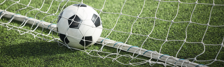 Medium angle of soccer ball in net on turf.
