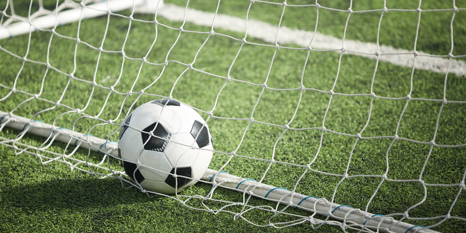 Medium angle of soccer ball in net on turf.