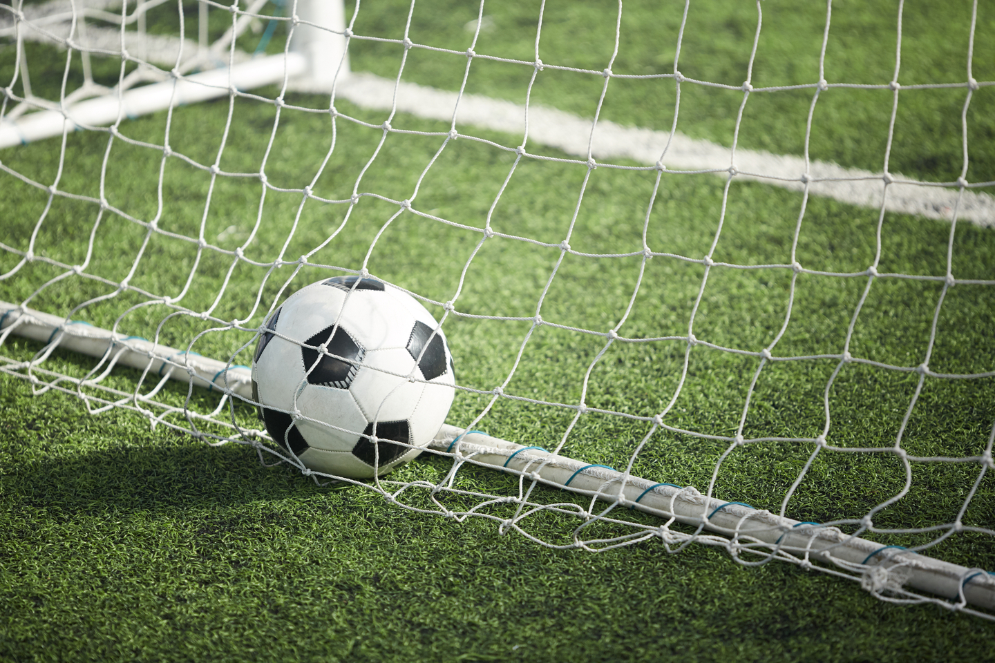 Medium angle of soccer ball in net on turf.