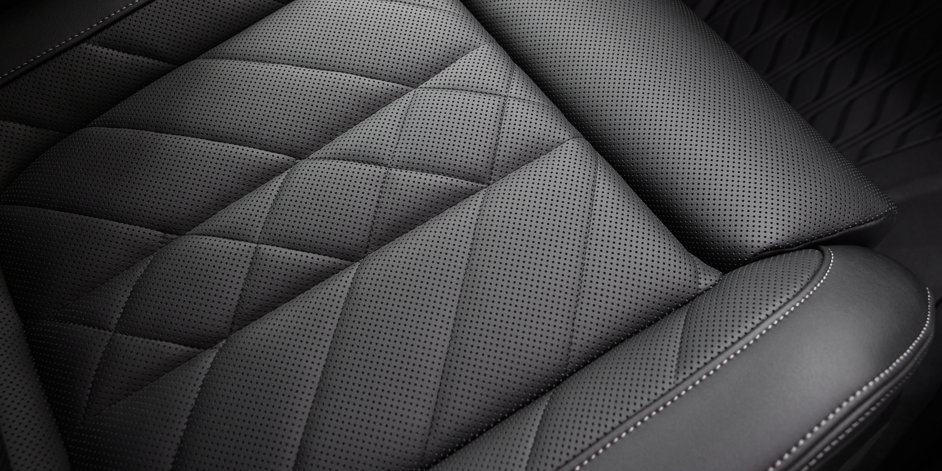 Black perforated leather seat surface with stitching details in a modern sporty car.
