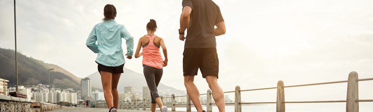 Medium angle of group of people running on a waterfront promenade.