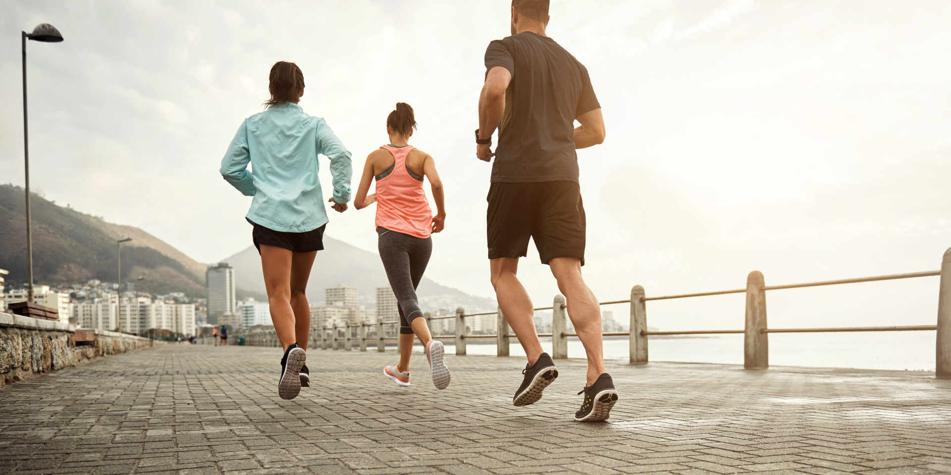 Medium angle of group of people running on a waterfront promenade.