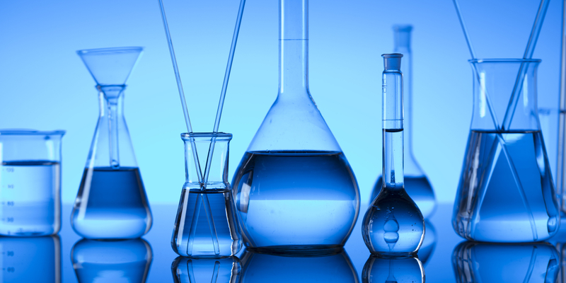 Medium angle of various scientific flasks on blue background.