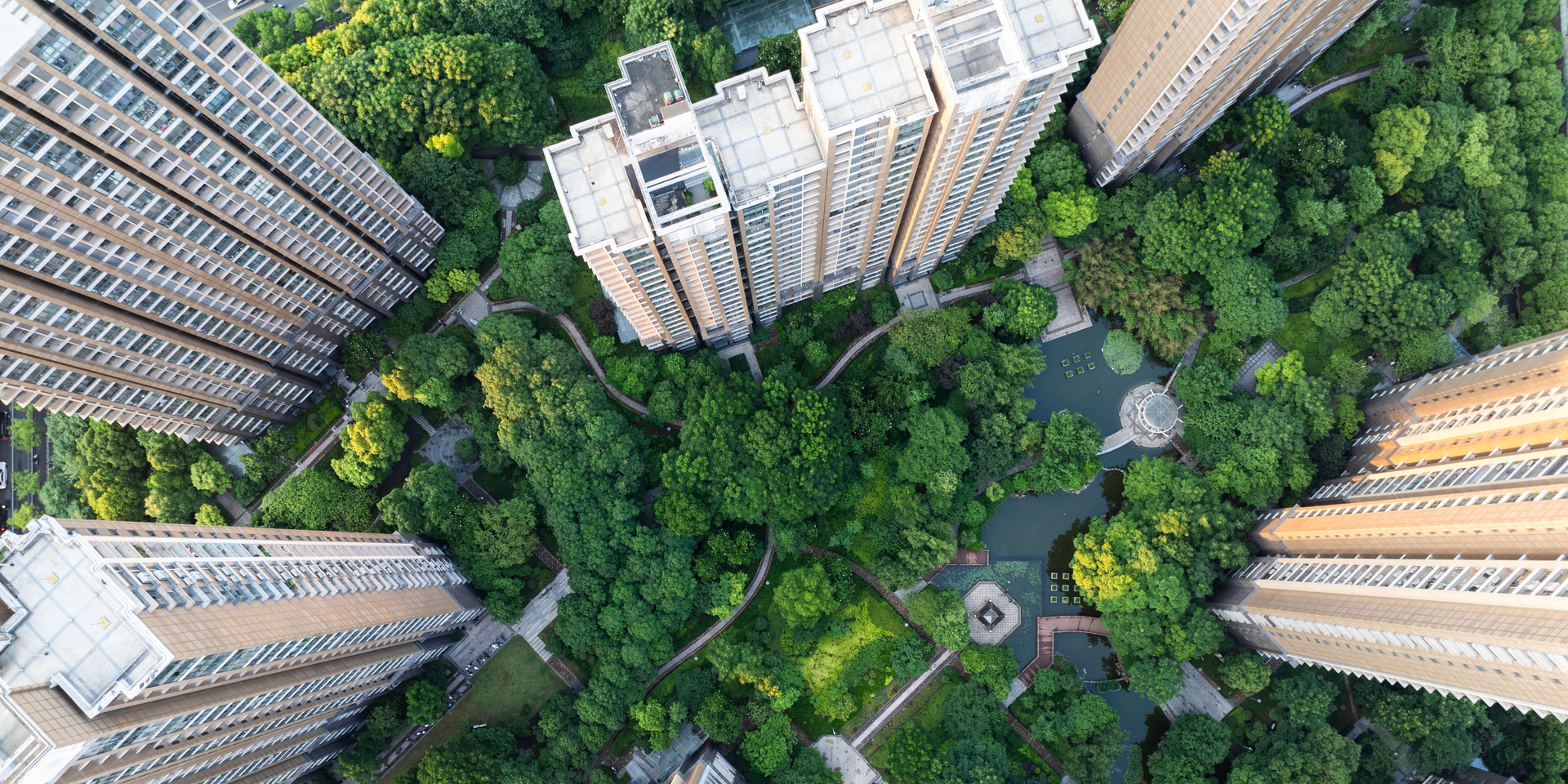 High angle down over multi-story residential buildings surrounded by trees.