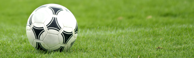 Close-up of soccer player kicking soccer ball.