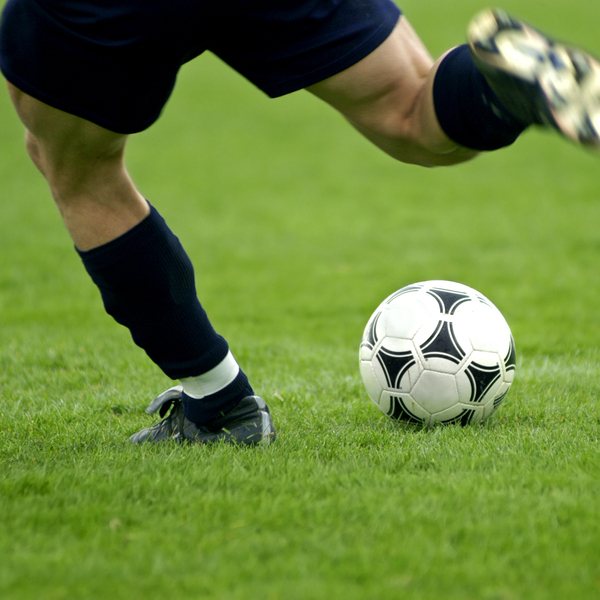 Close-up of soccer player kicking soccer ball.