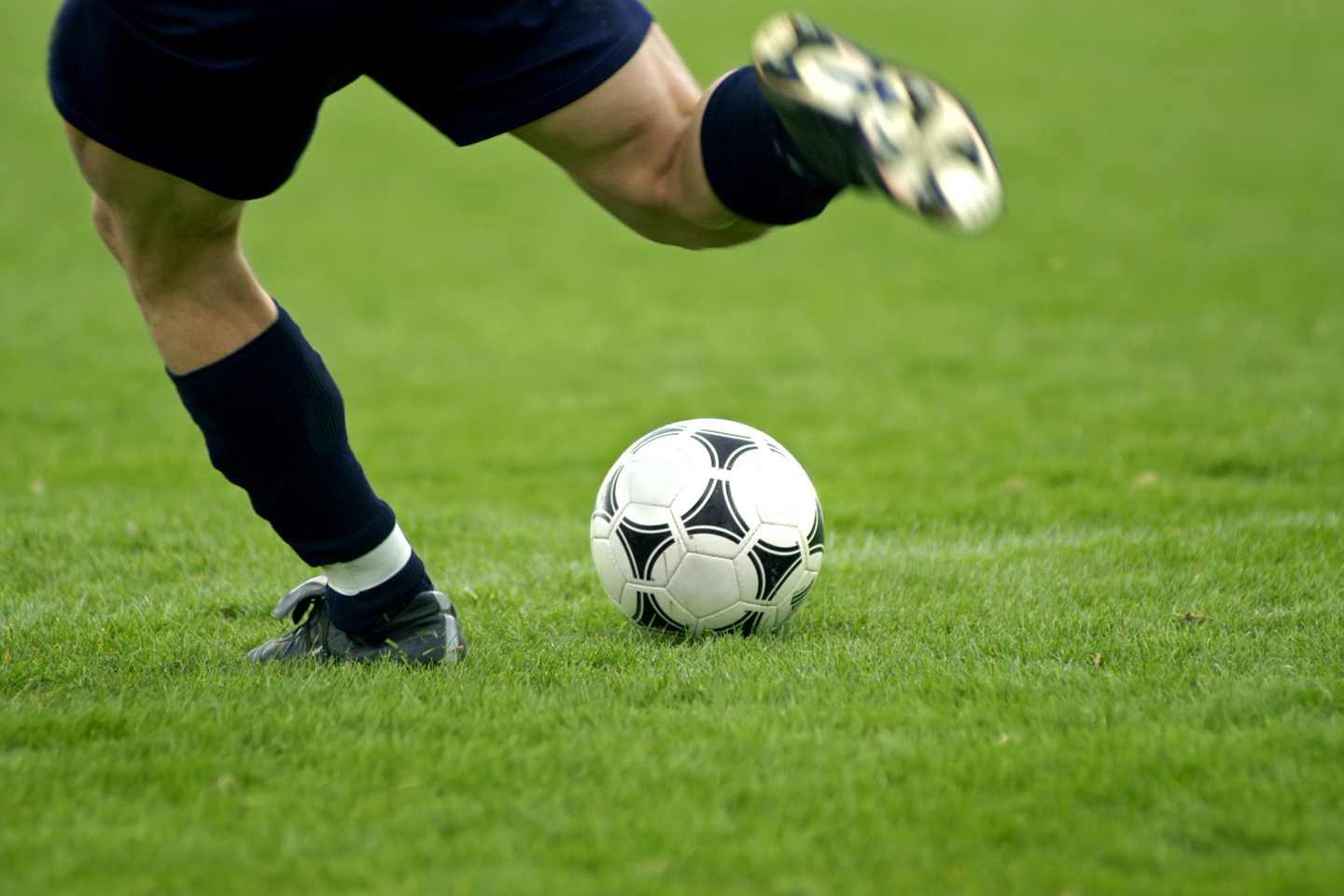 Close-up of soccer player kicking soccer ball.
