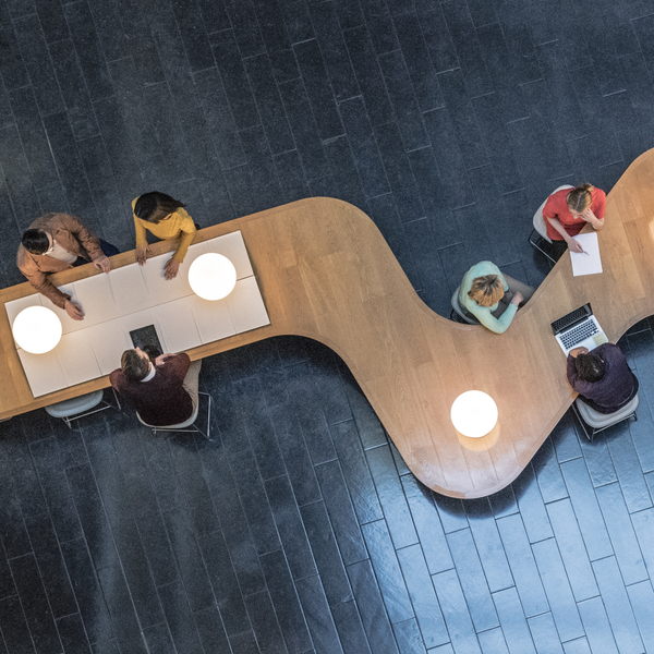 High angle down of coworkers meeting in communal area of a modern office space.