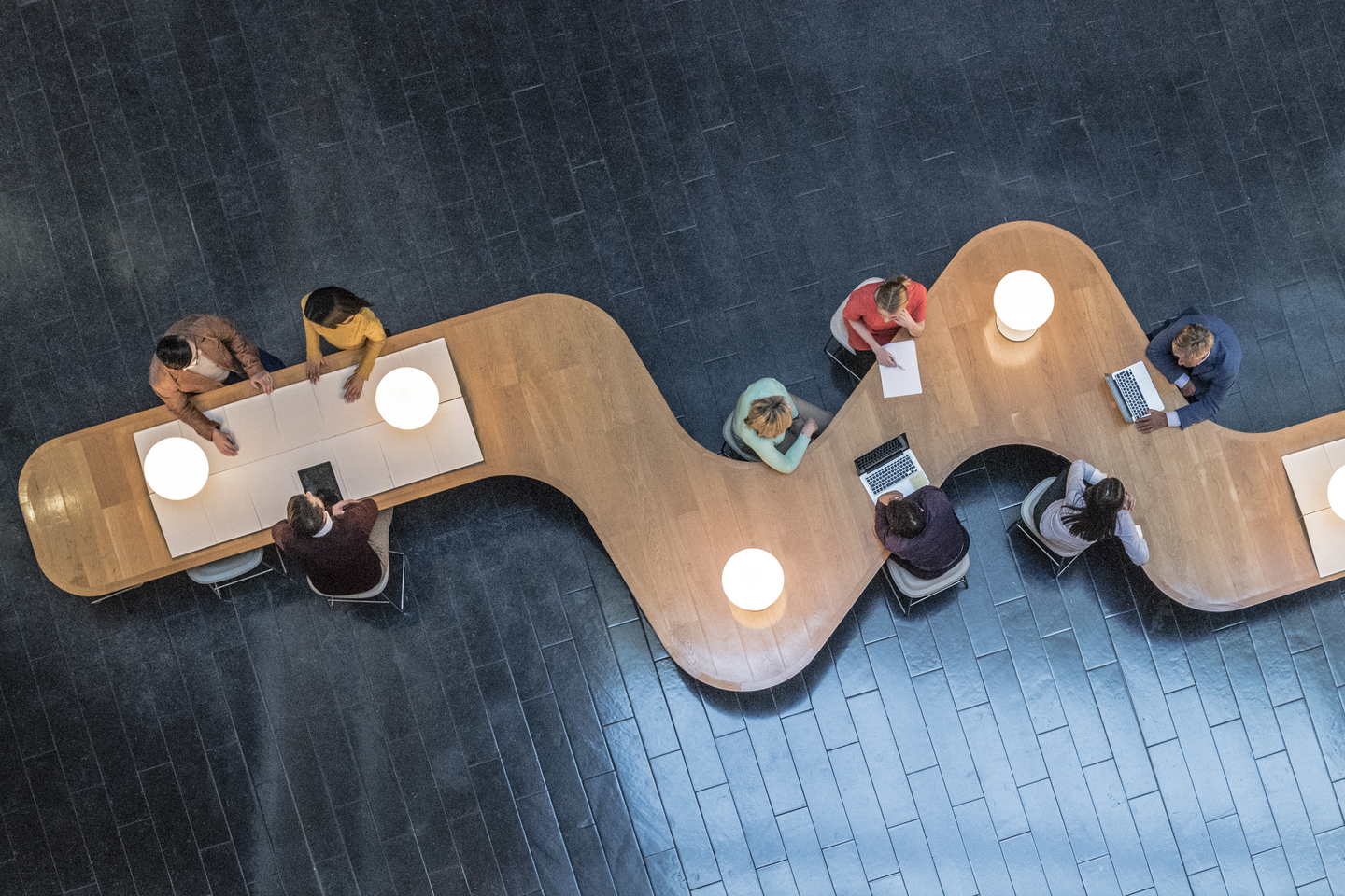 High angle down of coworkers meeting in communal area of a modern office space.