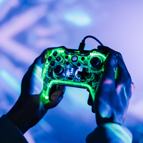 A man with a neon joystick in the dark playing video game on a computer.