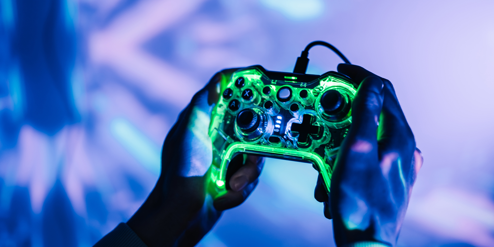 A man with a neon joystick in the dark playing video game on a computer.