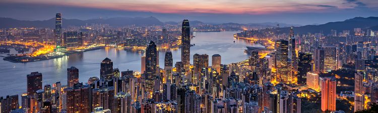 Wide angle of Hong Kong city skyline and Victoria Harbor at dusk.
