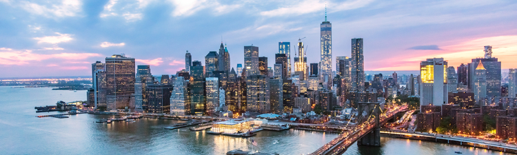 Aerial of lower Manhattan city skyline, Brooklyn Bridge, and East River at dusk,