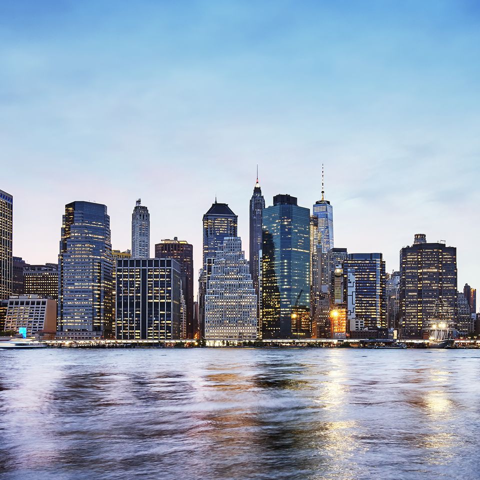Panoramic view of Manhattan skyline at dusk from East River and Brooklyn Bridge Park.