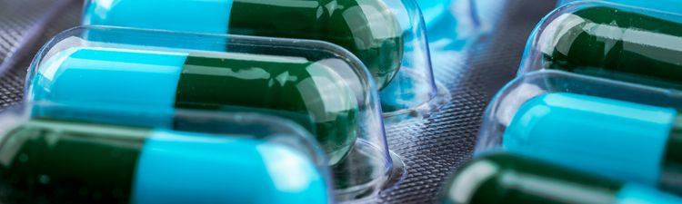 Close-up of green and blue pill capsules in blister pack.