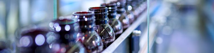 Close-up of brown glass bottles on production line.