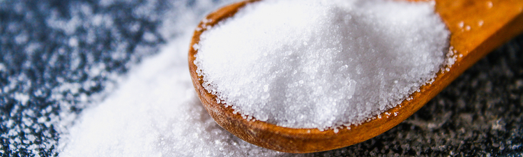 Close-up of salt crystals in wooden spoon.