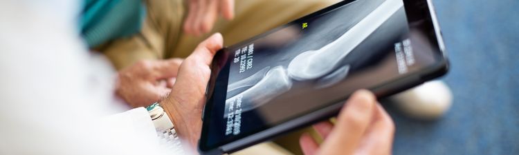 Close-up of medical professional reviewing medical imagery with patient on digital tablet.