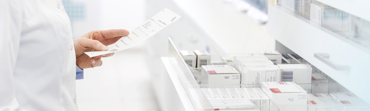 Medium angle of pharmacist looking for prescription drugs in drawer at pharmacy.