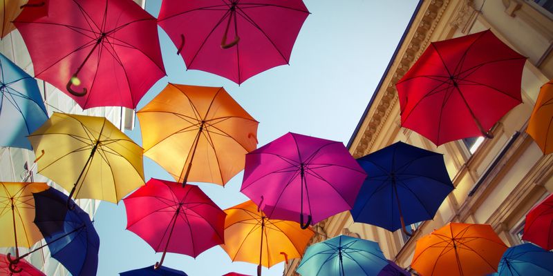 Up angle of colorful umbrella art installation over city street.