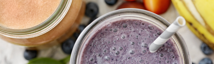 High angle down close-up of purple smoothie in glass with straw.