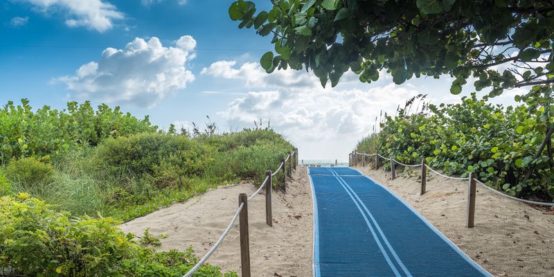 Wide angle of blue, beach access ramp for those with physical impairments.