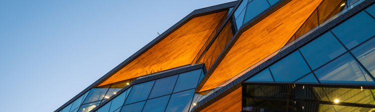 Contemporary architecture featuring curved glass panels and geometric orange accents against blue sky