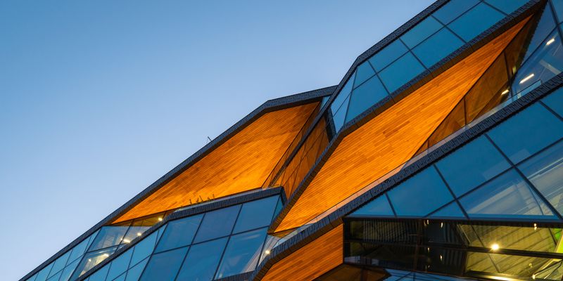 Contemporary architecture featuring curved glass panels and geometric orange accents against blue sky