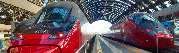 Medium angle of red Italo train parked at station.