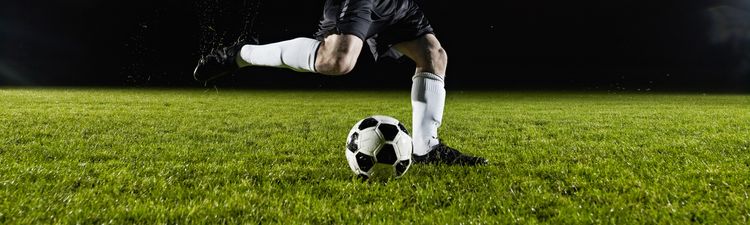 Wide angle of soccer player kicking ball on field.