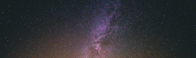 Wide angle of silhouetted person standing against starry night sky.