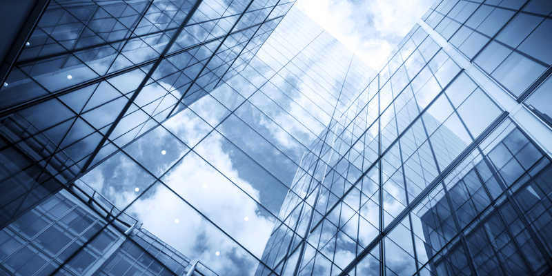 view of a contemporary glass skyscraper reflecting the blue sky and clouds