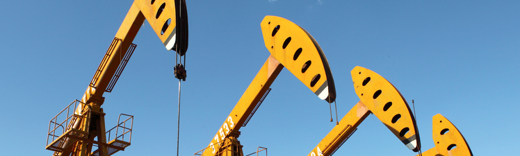 Medium angle of row of yellow oil pumpjacks.