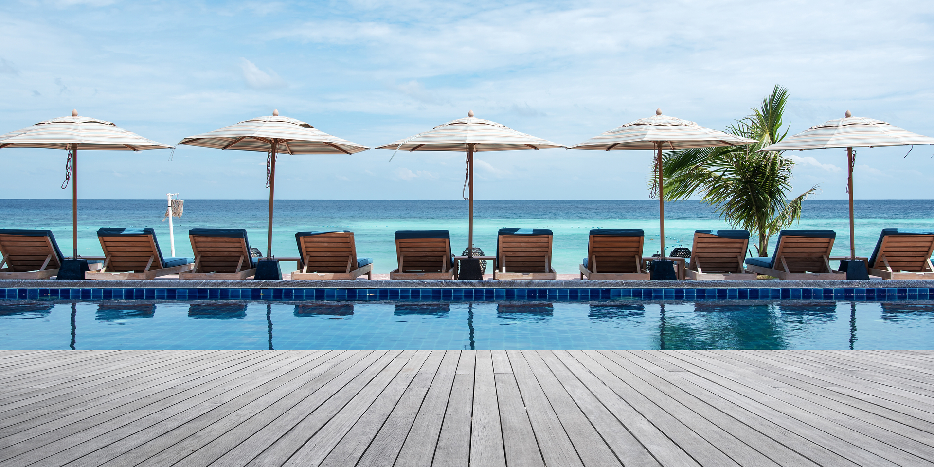 Wooden terrace beside tropical beach swimming pool