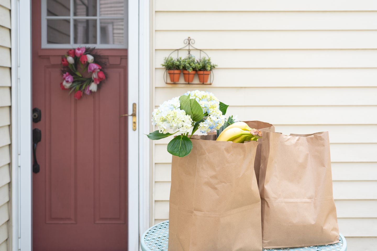 Medium angle of brown paper grocery bags outside front door of house.