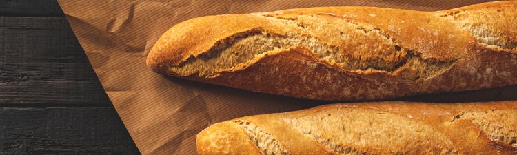 Close-up of French bread rolls on butcher paper in bakery.